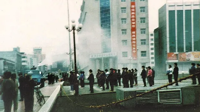 Полицаи използват хидравлично оръдие, за да пръскат вода върху последователи на Фалун Дафа, изпълняващи групови упражнения.