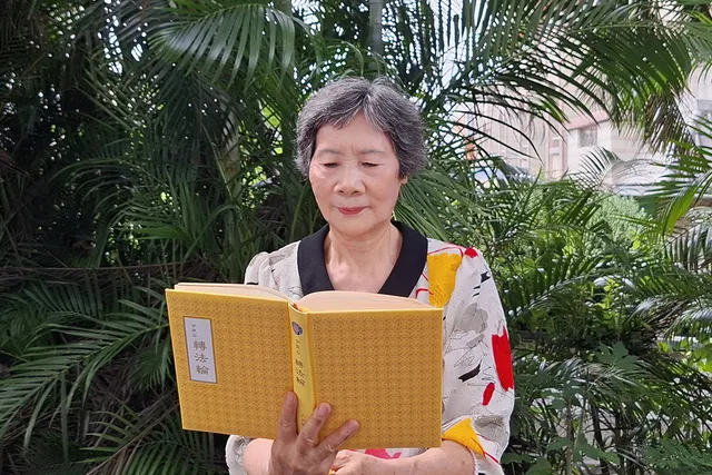 Възрастна китайка чете книгата "Джуан Фалун" на китайски.