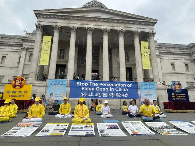 Последователи на Фалун Дафа медитират заобилколени от информационни банери.