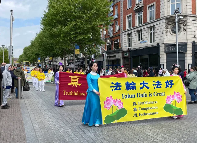 Последователи на Фалун Дафа държат информационни банери за Фалун Дафа в парад.