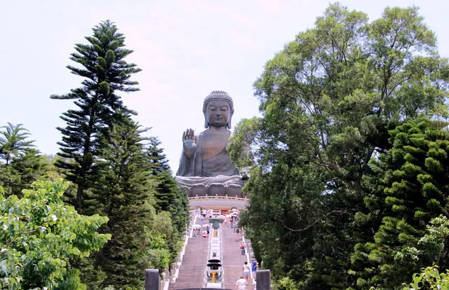 Голяма Буда статуя на остров Лантау. Голяма Буда статуя на остров Лантау, и пътека, водеща към нея с посетители, обкръжени от високи зелени дървета.