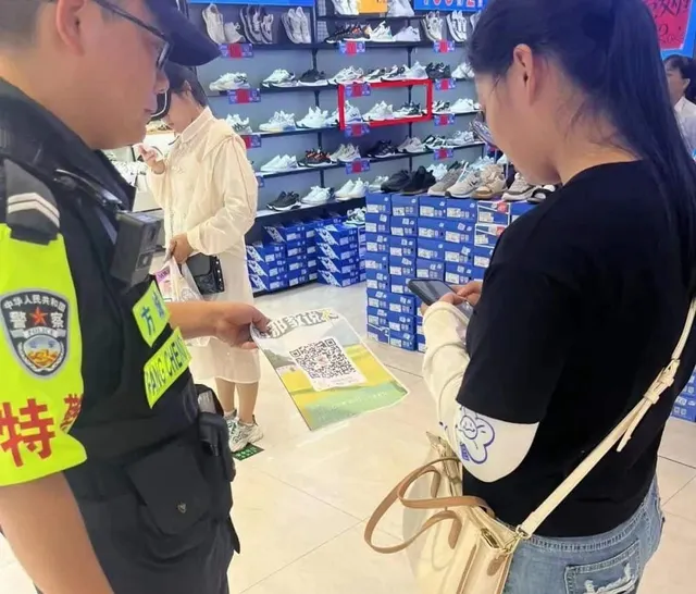 Полицай стои с листовка в ръка и чака жената до него да се подпише на телефона си.