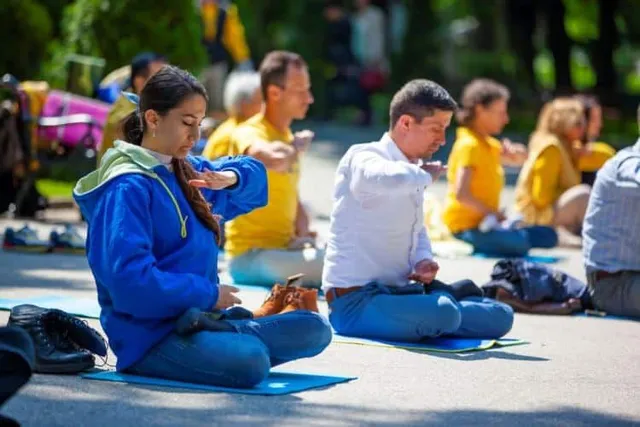 Група хора правят медитативно упражнение на Фалун Дафа с кръстосани крака. Група хора правят медитативно упражнение на Фалун Дафа с кръстосани крака върху постелки навън.